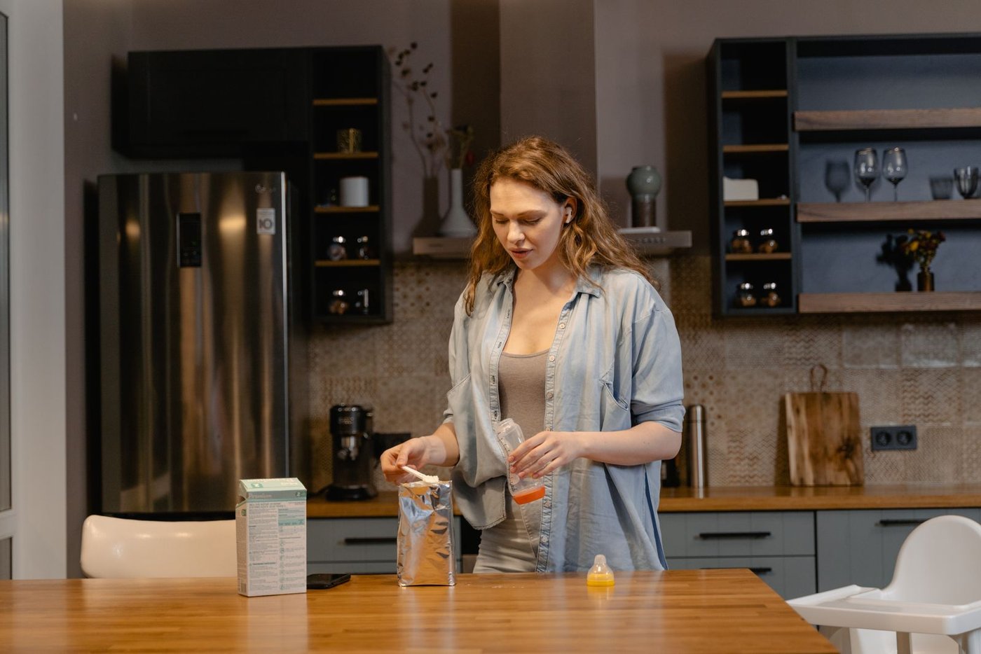 A parent preparing a baby bottle in a kitchen
