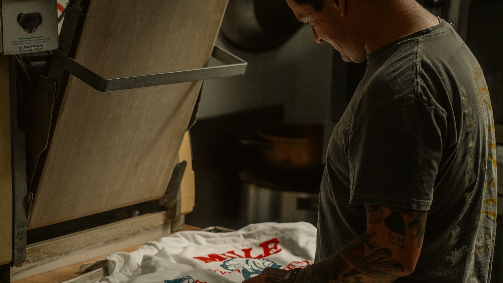 A worker prepares a custom T-shirt with a heat press